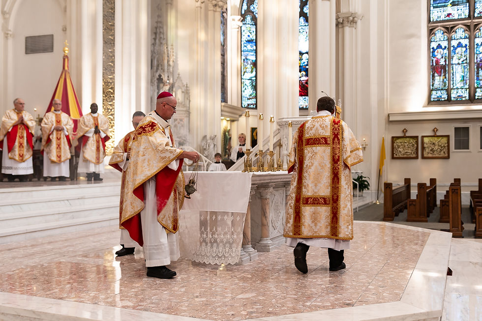 Catholic clergy in ornate red-and-gold vestments process around a marble altar inside a bright church with stained-glass windows.