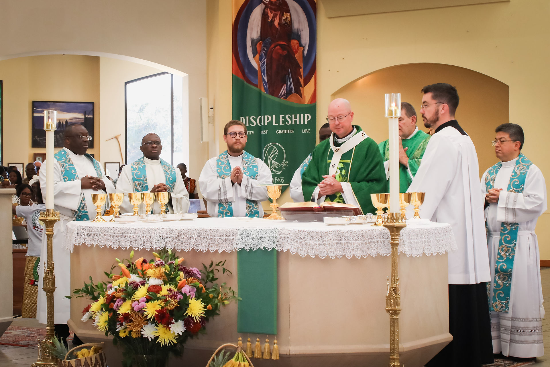 Priests stand in prayer around a church altar with gold chalices; green banner reads DISCIPLESHIP.