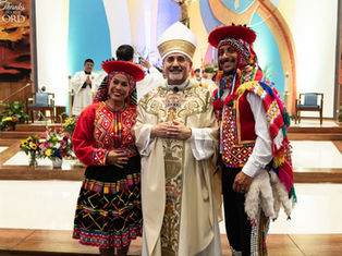 Smiling trio in colorful traditional dress pose inside a church altar; banners read Thanks to the LORD.