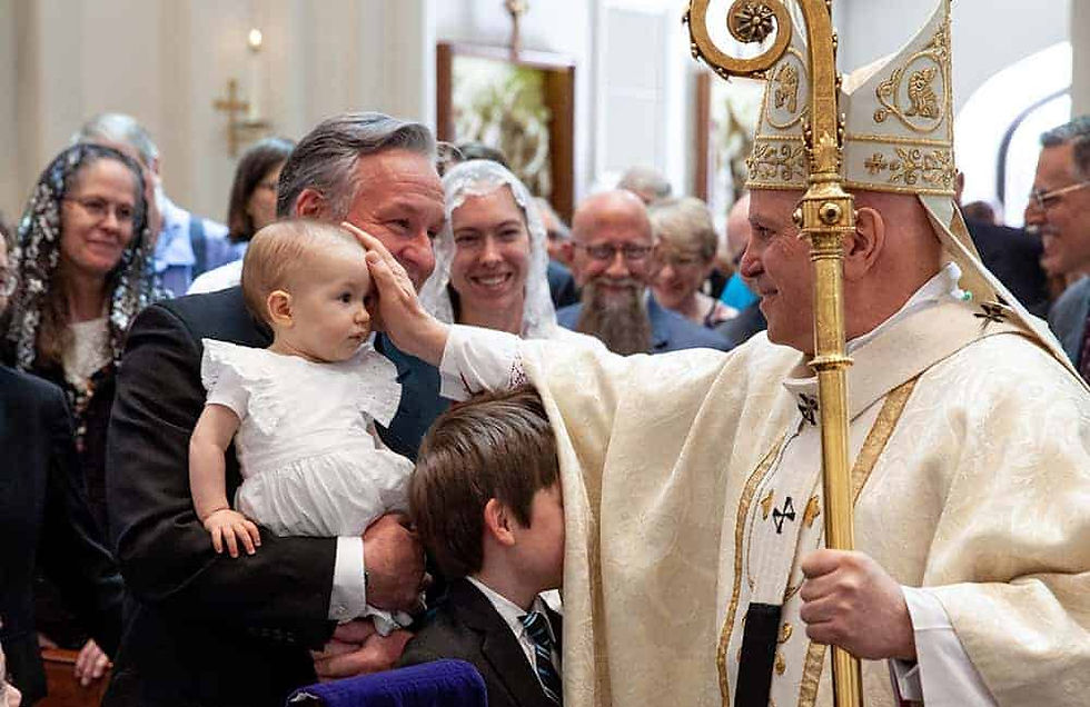 Archbishop Aquila blessing a baby