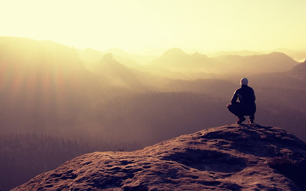 Hiker sits on a rocky peak and enjoy the scenery