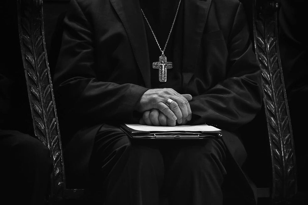 Priest wearing crucifix and has folded hands