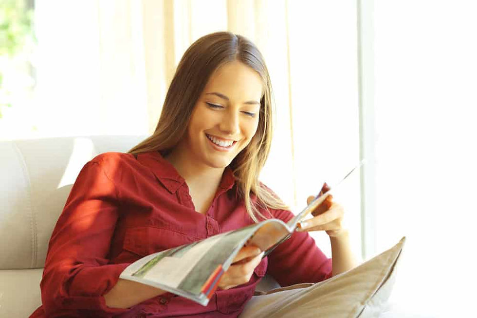 A woman relaxes on a couch, reading the Denver Catholic magazine in a serene, inviting space.