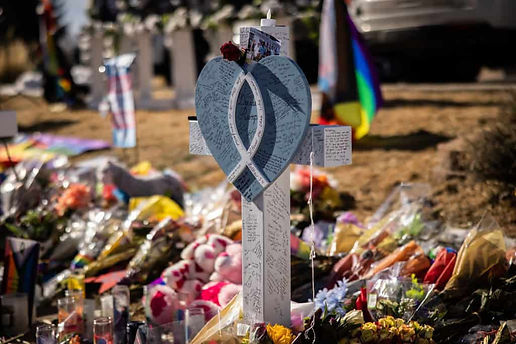 A memorial including a cross and flowers outside of Club Q