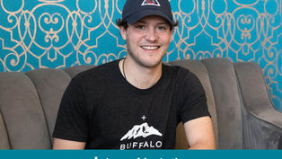 Man in a cap and "Buffalo" shirt smiles on a gray couch. Blue patterned wall behind. Text at bottom reads "Appeal in Action."