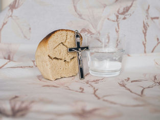 A piece of bread, a crucifix, and a glass of water representing Lent