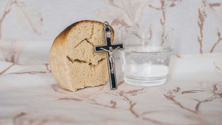 A piece of bread, a crucifix, and a glass of water representing Lent