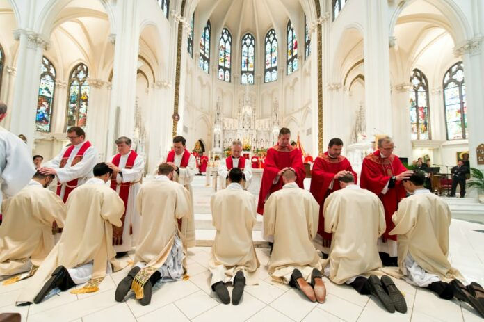 Priests lay hands on soon-to-be-ordained deacons