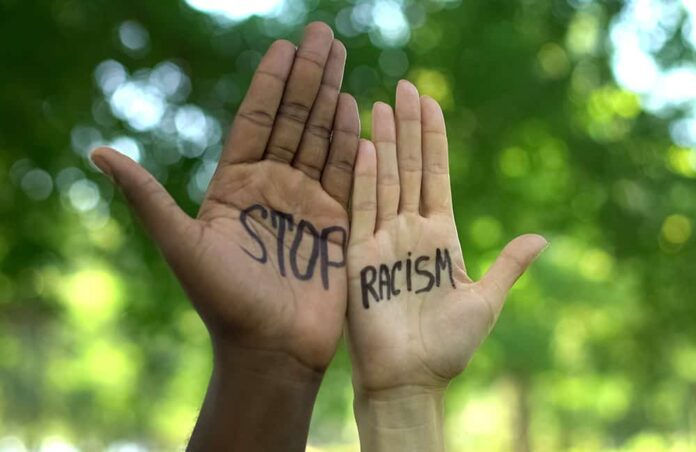 Interracial people hands with stop racism phrase, fight against discrimination (Photo: Adobe Stock)