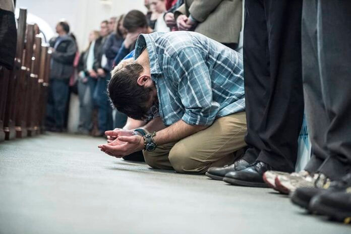 Men bent over in prayer