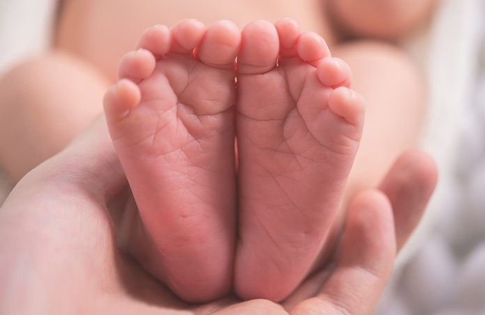 Hand holding infant's feet
