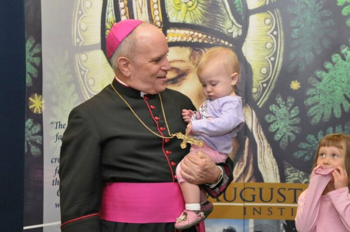 Archbishop Aquila holding a baby