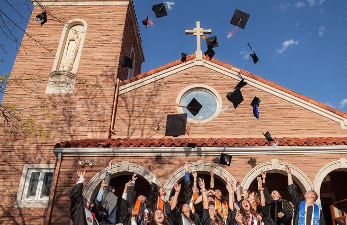 Graduates throwing up their caps in front on a church