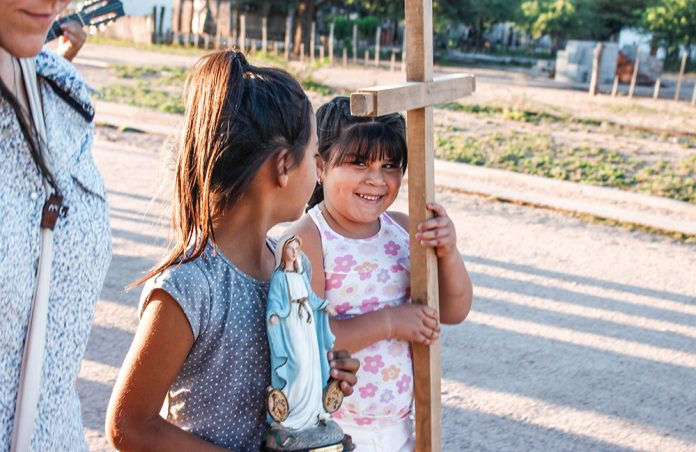 One girl holding Mary statue and one girl holding a cross