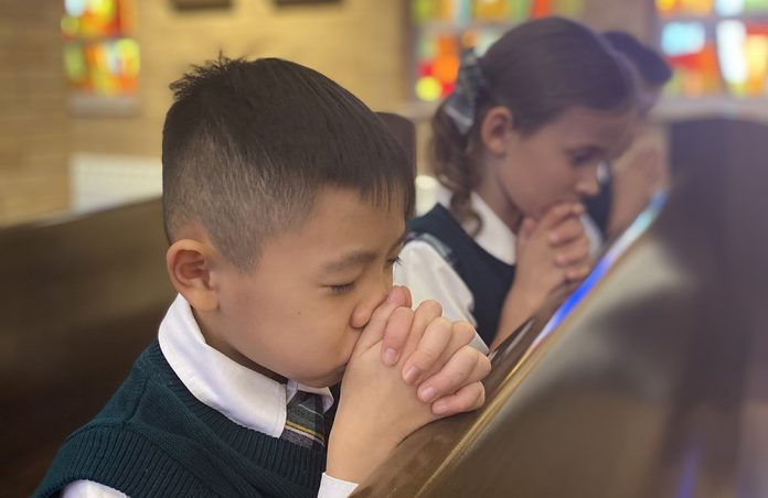 Kids praying in pews