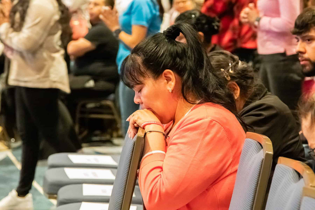 Woman kneeling during the Mass while people go to receive the Eucharist