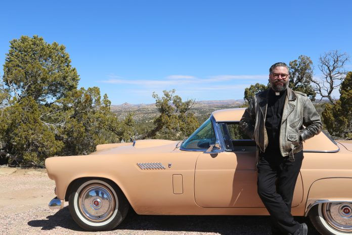 Deacon Aaron Alford poses with a newly restored Firebird, part of the annual V8 for Vocations fundraiser. (Photo courtesy of V8 for Vocations)