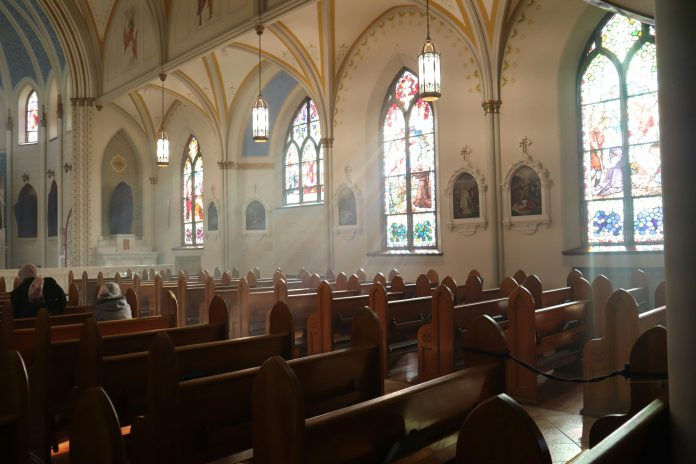 Church with many pews and with light streaming through the windows