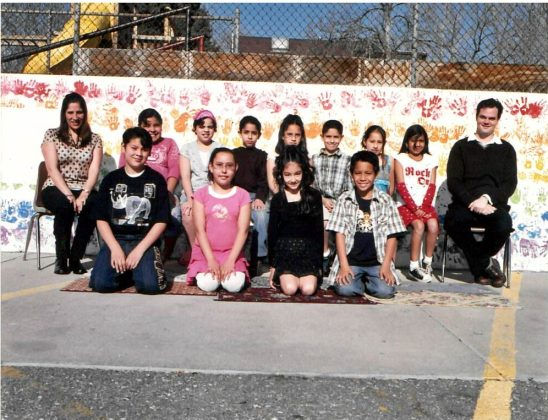 Mariella Robledo, Escuela's principal who celebrates 20 years with the school this year, sits for a class picture with a class in the early 2000s. (Photo provided)