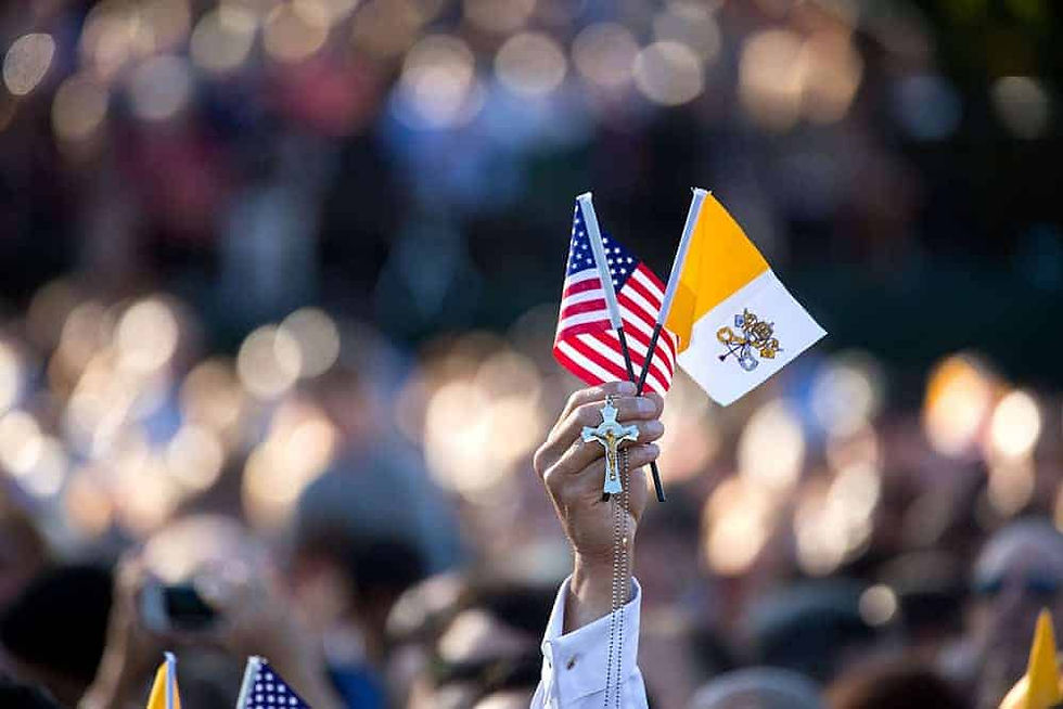 Hand holding crucifix, American flag, and Vatican flag