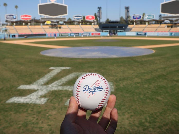 Hand holding baseball in front of a baseball stadium